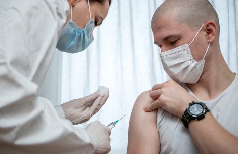 Doctor preparing to inject a male patient with antiviral vaccine.