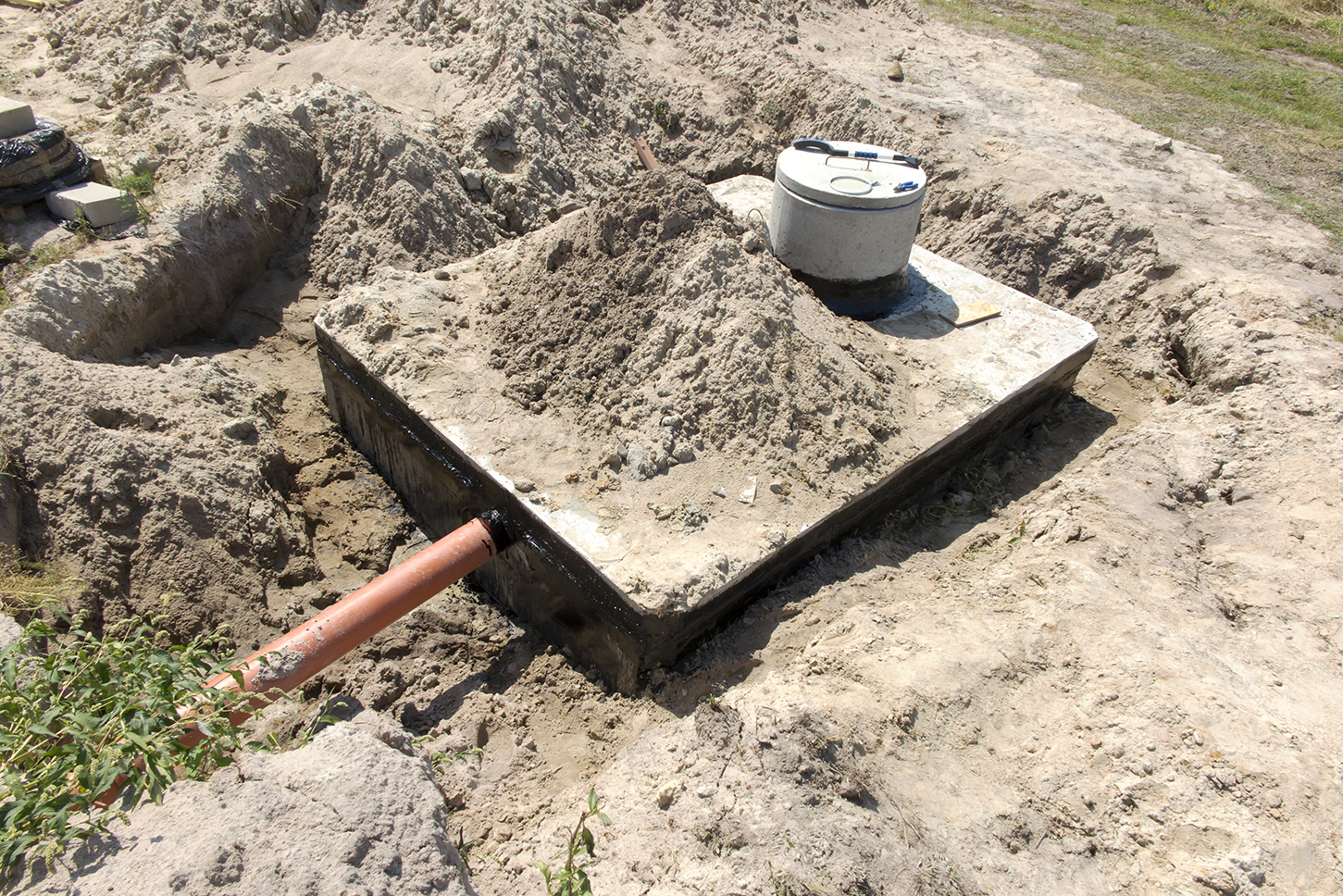 An image showing a concrete onsite wastewater treatment system surrounded by dirt. 