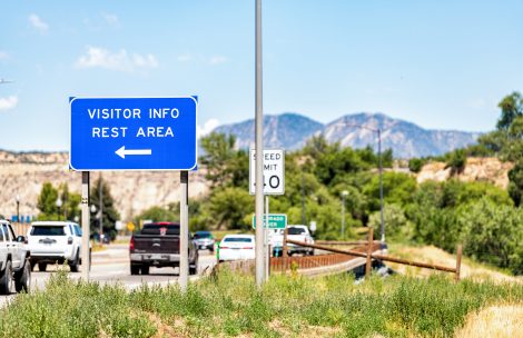 Sign for visitor center info and rest area exit on Interstate 70 near Rifle, Colorado during summer.