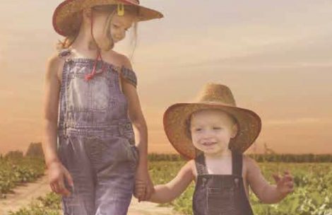 Cover image from the 2022 Garfield County Fair and Rodeo fair book. showing two farm kids walking down a dirt road.