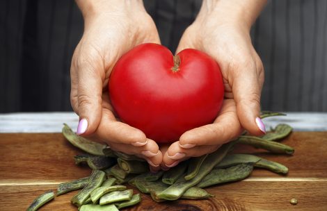Tomato in the shape of a heart in female hands.