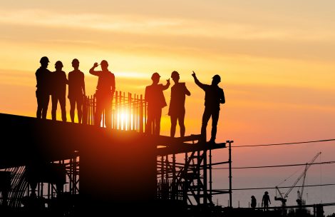 Industrial sector construction site with workers at sunset in evening time.