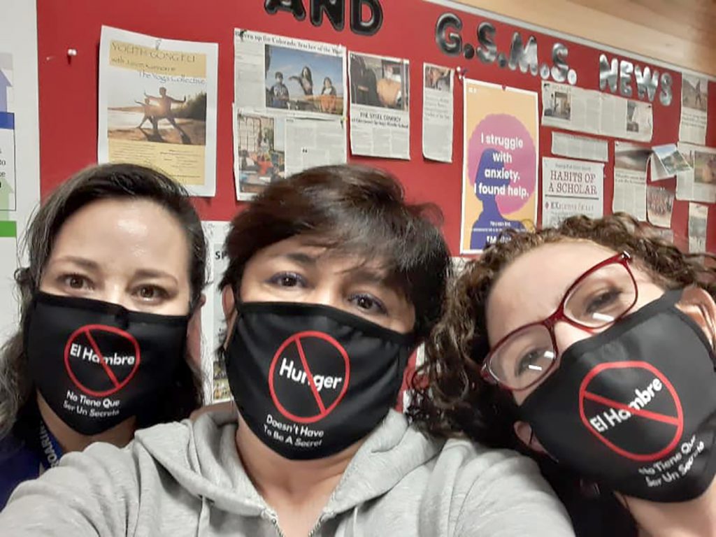 Three volunteers at the Safe and Abundant Nutrition Alliance (SANA) wear masks promoting its new "hunger doesn't have to be a secret" campaign.